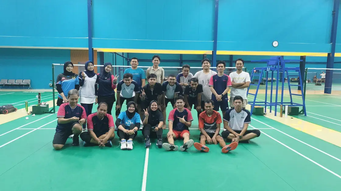 Para pemain berfoto bersama di lapangan hijau setelah kegiatan badminton.