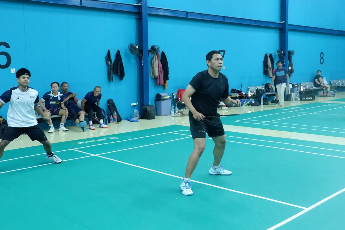 Aksi pemain dengan anggota menyaksikan di tepi lapangan.