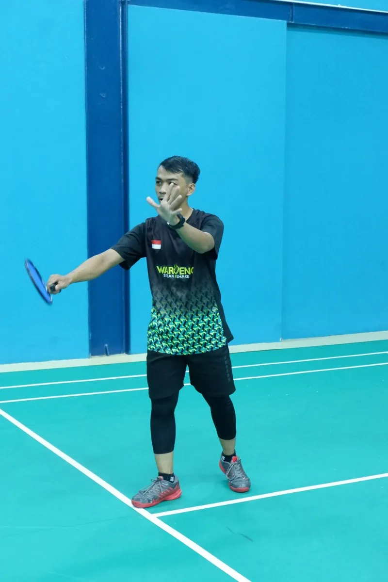 Pemain mengayunkan raket dalam pertandingan.