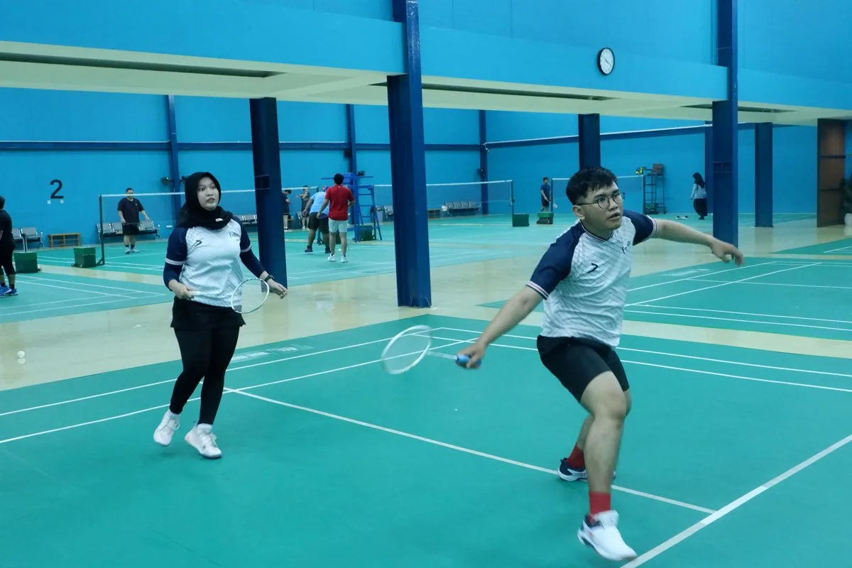 Pasangan berjersey Fokus Badminton mengejar kok.