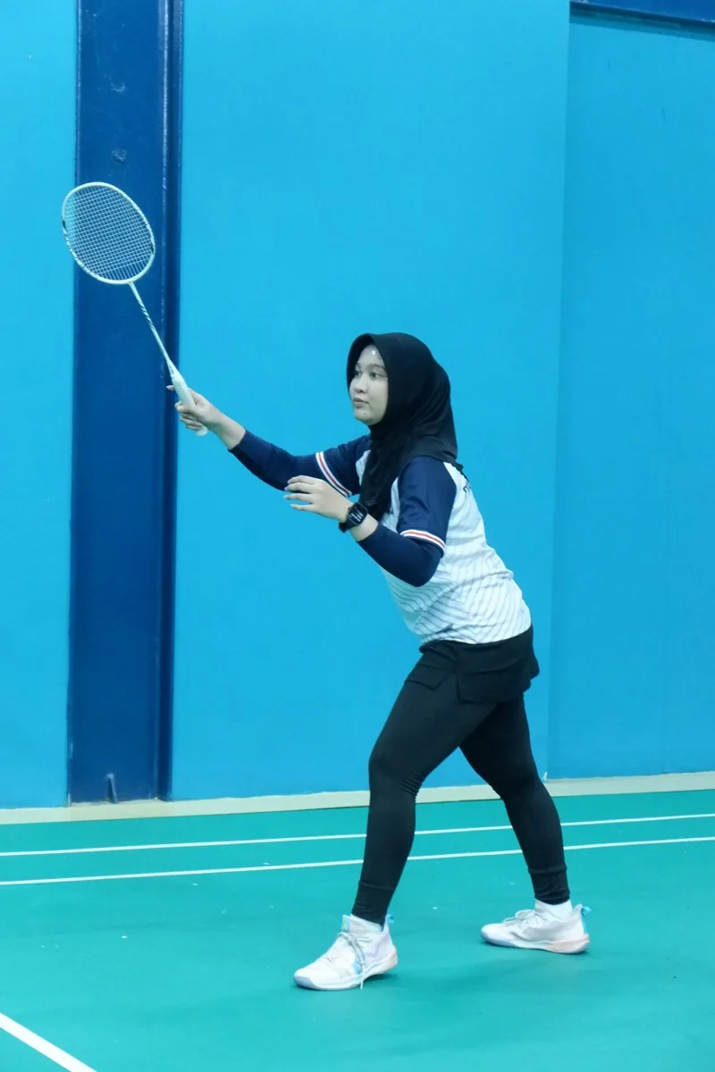 Pemain perempuan mengangkat raket.