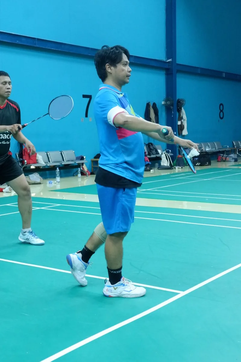 Pemain berjersey biru bersiap melakukan servis.
