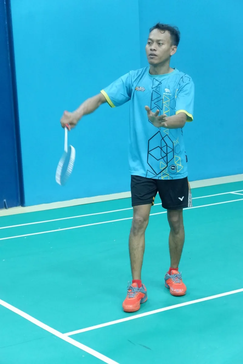 Pemain berjersey biru melakukan servis.