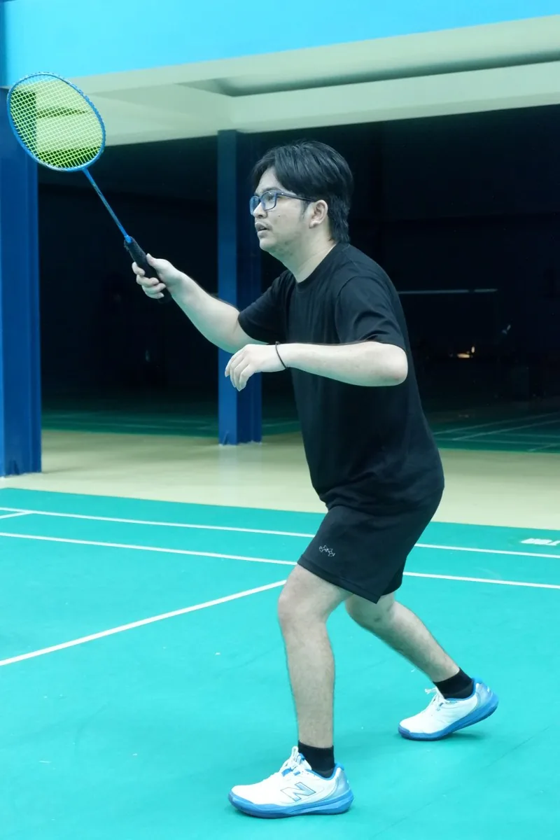 Pemain berkacamata bersiap dengan raket.