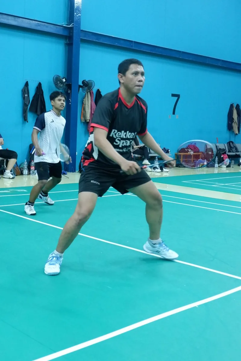 Pemain berjersey hitam merah dalam posisi siap.